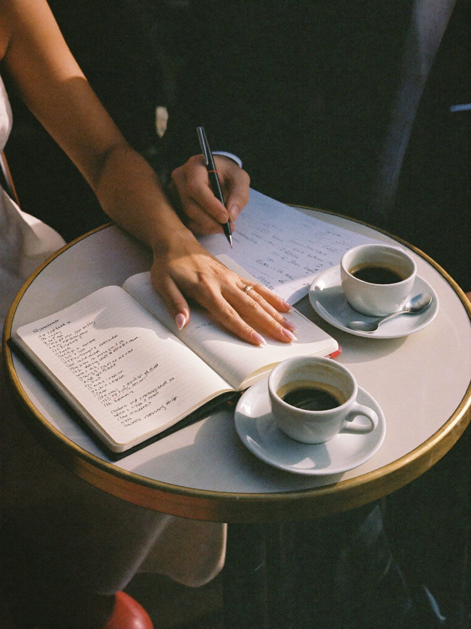Manos de una pareja planificando su boda con un cuaderno y dos cafés